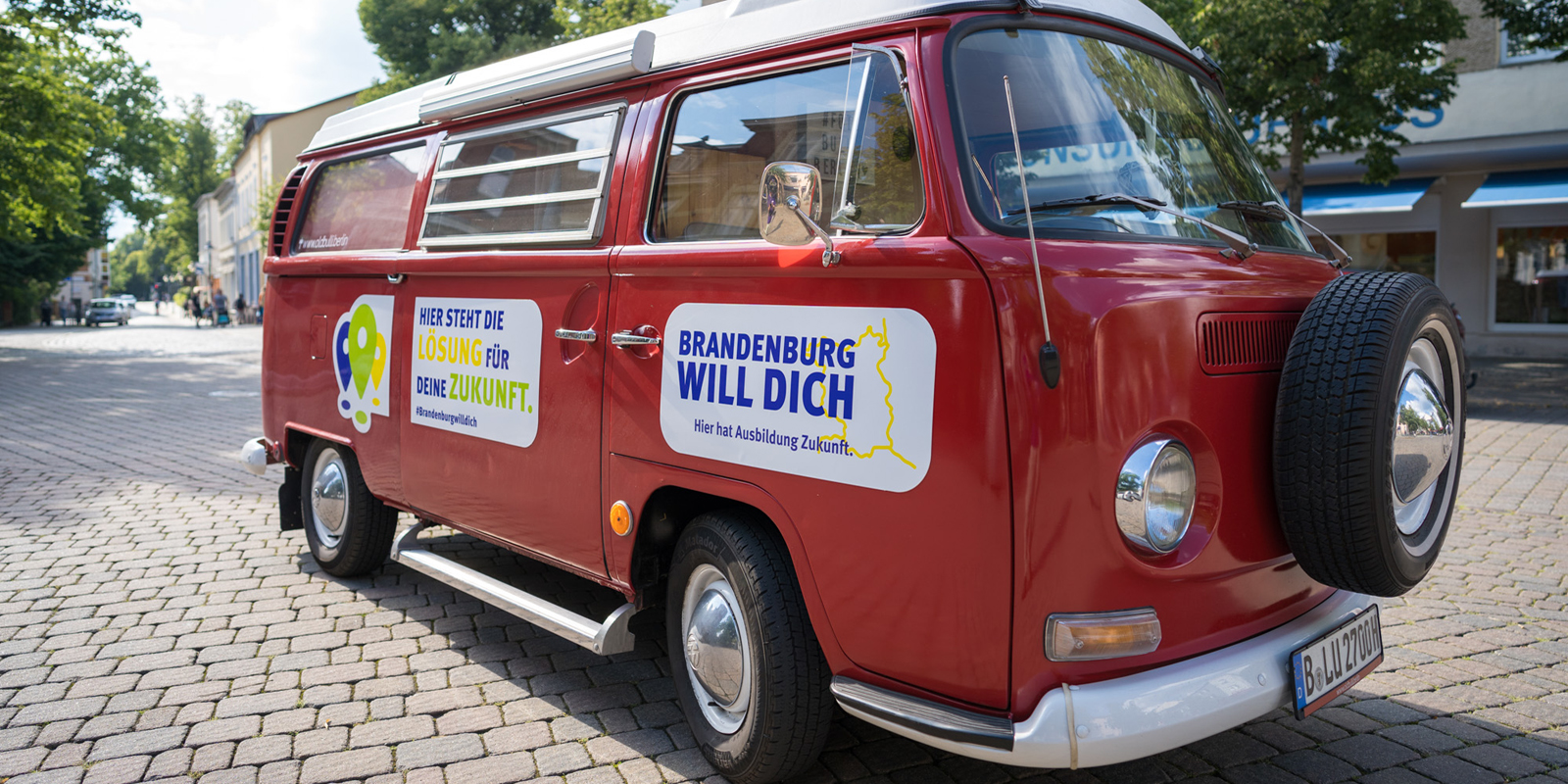 Auf dem Foto ist ein roter Bulli zu sehen. Darauf steht "Brandenburg will dich".