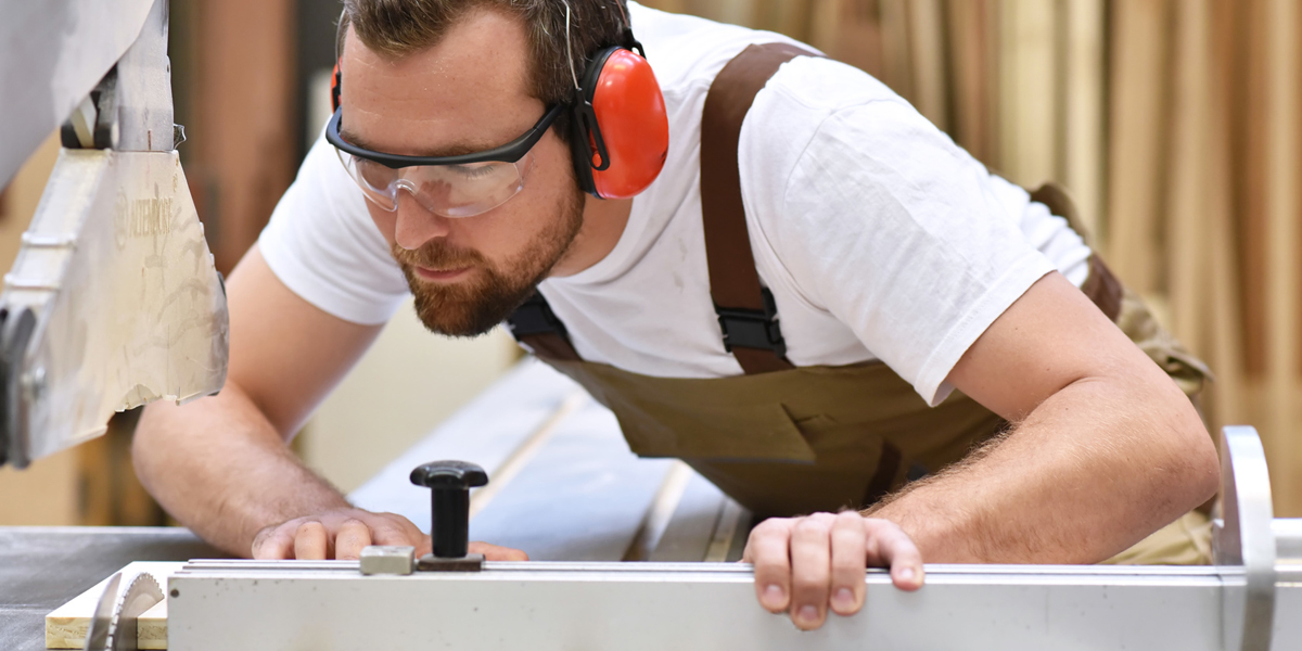 Tischler in einer Schreinerei sägt ein Holzbrett an einer Sägemaschine, Foto: © industrieblick / Fotolia