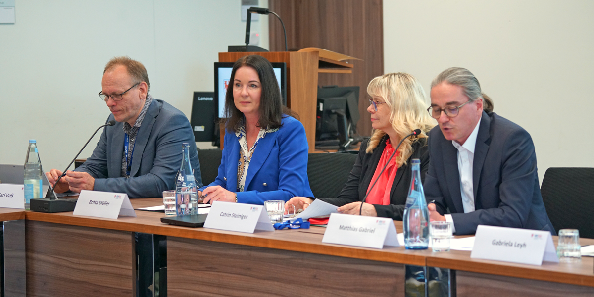 Das Foto zeigt Gesundheitsministerin Britta Müller beim "Runden Tisch Impfen", die mit weiteren Teilnehmenden an einem Tisch sitzt und spricht.